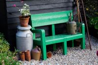 Painted green bench next to a shed with old milk churn and watering can - 'The Home Front Garden', Bronze Medal Winner, RHS Hampton Court Flower Show 2011 