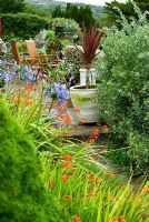 View along terrace framed by agapanthus and crocosmia
