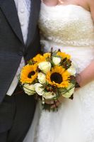 wedding bouquet of white roses and sunflower held by a bride