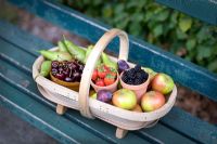 small wooden trug on a blue green bench containing British fruit 