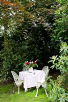White metal chairs and table in shady garden