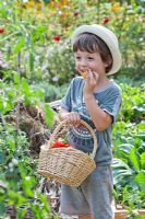 Boy with wicker basket of freshly harvested vegetables.
