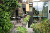 Seating area on decked patio surrounded with raised beds and containers, Deborah Nagan, garden, London
 