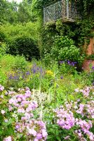 Pink Phlox paniculata 'Propsero', white Veronicastrum, blue Veronica spicata and yellow Rudbeckia fulgida 'Goldsturm' mix in the stone garden around the house - Holbrook Garden, Tiverton, Devon, UK