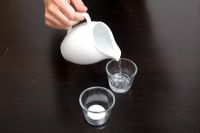 Pouring water into glass for floating tea light candle 