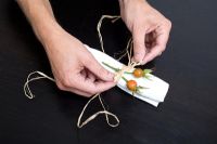 Man tying decorative seed heads to napkin 