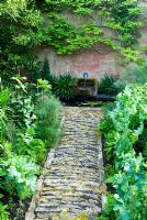 Stone path leading to small water feature between beds 