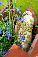 Plaster angel tucked into flower pot with lobelia flowers