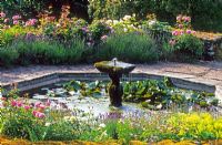 Octagonal pool with fountain surrounded by Rosa 'Mary Rose', Alchemilla mollis and Lavender - High Glanau Manor, Monmouthshire, Wales 
 