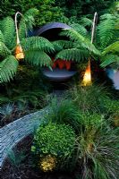Modern lighting and covered seating area surrounded by Dicksonia antarctica and Polystichum setiferum ferns 