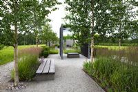 Modern minimal garden with benches made from timber and steel, Betula - Birch trees and rectangular beds of grasses