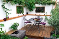 Alfresco dining area in a contemporary small garden, with scented herbs planted in vertical wall boxes. 