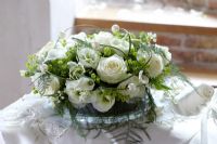 Wedding floral arrangement of Alchemilla mollis, Rosa, Aralia and Eustoma 'Mariachi Green', Zantedeschia and Convallaria
 