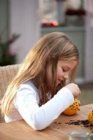 Child making Christmas decorations, sticking cloves in oranges
