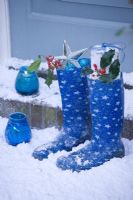 Candles on door step with blue boots and Holly sprigs