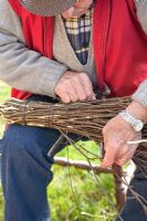Making a Birch broom -  man tying  inside part of the broom with steel wire, once more