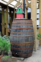Large wooden rainwater barrel for recycling water from the roof with house shaped bird nest on top - Dalston Eastern Curve Garden, London Borough of Hackney, UK