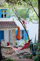 Colourful deckchairs and parasol in Mediterranean courtyard garden