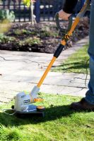 Using strimmer to cut lawn