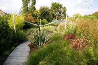 Garden view with sail, Phormiums, Pennisetum, Cortaderia and Miscanthus - Farrs, Dorset