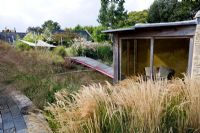 View of summerhouse with Stipa calamagrostis and Molinia 'Transparent' - Farrs, Dorset