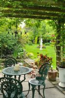 View from pergola with table and chairs to formal pond and lawn beyond - The Rowans, Threapwood, Cheshire.
