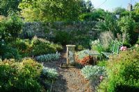 Formal garden with blue painted wrought iron bench, old sundial, gravel paths, Roses and herbaceous perennials - Barnwells, Cerne Abbas, Dorset.