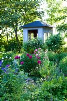 Wooden tea house in herb garden surrounded by Origanum vulgare, Thymus, Echinacea, Sidalcea, Rosa, Lavandula, Verbascum, Malva, Paeony, Salvia