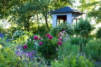 Wooden tea house in herb garden surrounded by Origanum vulgare, Thymus, Echinacea, Sidalcea, Rosa, Lavandula, Verbascum, Malva, Paeony, Salvia
