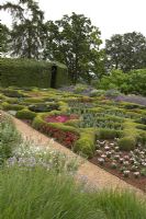 The Broughton Grange Box parterre - the design is based on the structure of leaves viewed under a microscope infilled with blocks of colour through the year with different plants depending on the season. Buxus parterre with Verbena x hybrida, Cosmos, Antirrhinum and Kale with mature trees and a Hornbeam hedge in the background