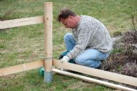 Man building a wooden fence