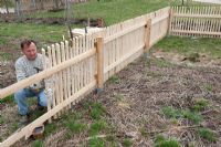 Man building a wooden picket fence