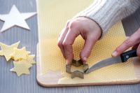 Making decorations - Star cut out of beeswax. Wood and star cookie cutter, knife and wooden board