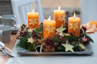 Advent wreath with Abies, stars cut from beeswax, Skimmia, cinnamon sticks and star anise in wooden bowl