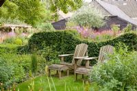 Wooden recliners backed by a clipped hedge of  Carpinus betulus - Ruinerwold Garden