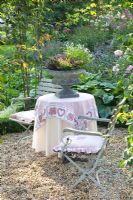 Seating area on gravel, surrounded by climbing roses - Tropical Touch