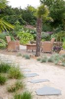 Stepping stone path leading to patio in tropical garden - plants include Trachycarpus fortunei and Festuca
