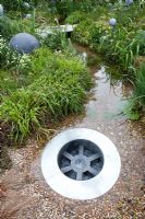 Hampton Court Flower Show. The WWF's garden, giant plug hole feature in stream