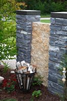 Fire basket with birch wood next to natural stone screen