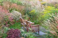 Seating area surrounded by Aster, Solidago, Sedum, Persicaria amplexicaulis and Miscanthus - Jacobs Nursery