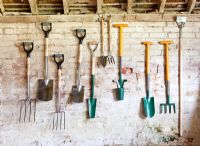 Gardening tools hanging up in a shed. Forks, spades, bulb planters and hoe