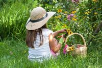 Girl picking flowers with secateurs and gathering them in a wicker basket