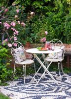 Patio with pebble mosaic floor, white metal table and chairs with cushions