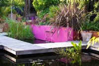 Pool with oak decking, Phormium, bright pink painted wall and letterbox fountain