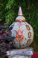 Mosaic shere with turkish tulip motif set on stone plinth surrounded by Verbascums
