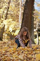 Girl playing with autumn leaves.