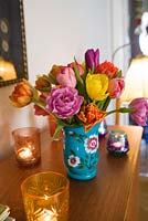 Tulips in vase on chest of drawers with candles in glass holders 