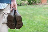Gardener holding muddy gardening boots