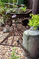 Old garden artefacts including a galvanised watering can, wheel barrow and top of a cold frame used for decoration