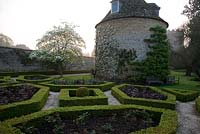 Pigeon House garden with pigeon house, 1685, and box parterre with Cornus nuttallii and new red leaves of hybrid tea roses. Rousham House